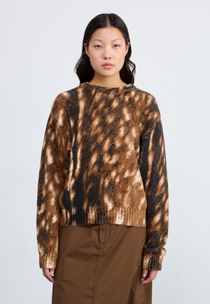 Strikket sweater med et brunt og sort dyreprint design, rund halsudskæring, ribbede manchetter og en afslappet pasform. Båret over en brun nederdel.