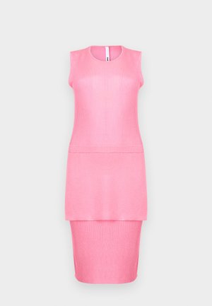 Ærmeløs lyserød ribstrikket kjole med lagdelt skørt og rund halsudskæring mod en ensfarvet lys baggrund.