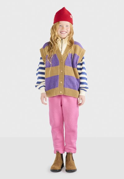 Brauner Strickwesten mit lila Streifen, über einem gestreiften Langarmshirt getragen, kombiniert mit rosa Hosen und braunen Stiefeletten.