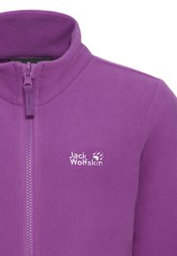 Veste polaire violette avec col montant, fermeture éclair intégrale et logo Jack Wolfskin blanc sur le côté gauche de la poitrine.