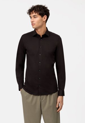Black long-sleeve shirt with a button-down collar, featuring black buttons and a tailored fit. Smooth, lightweight fabric with a sleek design.