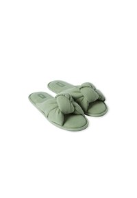 Pantofole di stoffa verde con un design a nodo davanti, texture morbida, suola piatta e soletta imbottita per il massimo comfort. Una leggera cucitura mette in risalto i bordi.