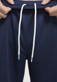 Pantalones cortos deportivos de color azul marino con cordones blancos, que cuentan con una cintura texturizada y una tela suave. Enfóquense en la zona de la cintura y el detalle del cordón.