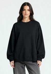 Fekete, oversized felső, kerek nyakkivágással, ejtett vállakkal és bordázott mandzsettákkal. Az anyag lágyan sima textúrájú.