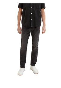 Camicia nera a maniche corte, abbinata a jeans slim-fit grigio scuro e sneakers bianche. Design semplice e pulito, senza motivi visibili.