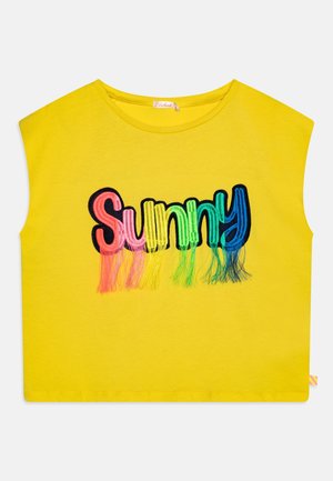 Gelbes ärmelloses Shirt mit dem Wort „Sunny“, das in Regenbogenfarben gestickt ist, mit Fransen, die von jedem Buchstaben hängen.
