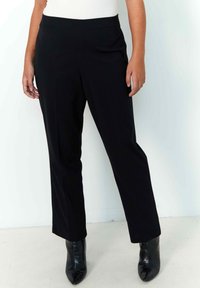Black tailored trousers with a smooth texture, featuring a straight leg design. Paired with pointed black ankle boots.