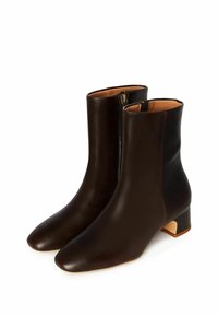 Stivali alla caviglia in pelle marrone con una texture liscia, punta rotonda, dettaglio con zip laterale e tacco basso a blocco.