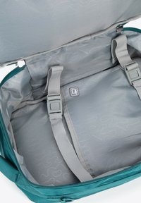 Wnętrze turkusowej torby materiałowej z gładką szarym podszyciem, z dwiema regulowanymi ramiączkami i metką na boku z prostym abstrakcyjnym wzorem.