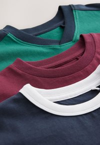 Kolm ümmarguse kaelusega t-särki, virnastatud. Värvid: roheline, burgundia, valge ja mereväe sinine. Resiinivarrukad ja pehme puuvillane materjal sujuvate tekstuuridega.