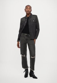 Must musta denim jakk, millel on kaks esipocketi, koos pisaratega mustade teksadega, mille lõpus on frayed cuffs. Kandmiseks mustade kandiliste ankle boots'itega.