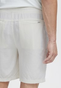 Lysfarvede linnedshorts har et tekstureret stof med elastisk talje og et lille mærke på baglommen.
