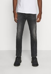 Tmavě šedé džíny s vybledlým povrchem, rovný střih a jemné efektové skvrny. V kombinaci s černými teniskami a bílým tričkem.