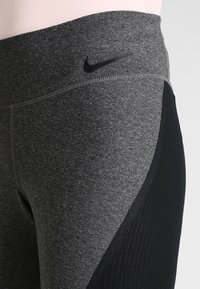 Leggings sportivi grigi con pannello laterale nero, cuciture piatte e un piccolo logo nero sulla vita.