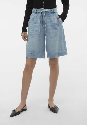 Lichtblauwe, knielange denim shorts met een trekkoord in de taille, zijzakken en omgeslagen manchetten; gecombineerd met zwarte slingback flats.