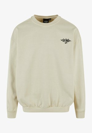 Béžová mikina z mäkkého materiálu, s okrúhlym výstrihom, dlhými rukávmi, rebrovanými manžetami a čiernym vyšívaným logom na hrudi.