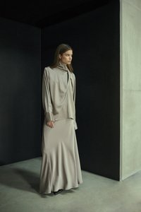 Lang, flydende kjole og top sæt i blød beige satin. Har en høj halsudskæring og løs pasform. Glat tekstur med minimal pynt.