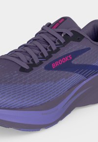Purple Brooks running shoe with pink branding, detailed laces, and a SpringRamp cushioned sole visible on a white background.