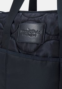 Marineblå quiltet stoftaske med læderpatch med Marc O'Polo logo. Har robuste flettede stropper og glat tekstur.