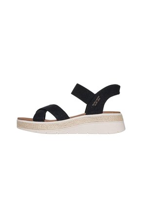 Sandalia con cuña negra con tiras de tela cruzadas, banda elástica en el tobillo, entresuela de yute beige y suela exterior de goma blanca.