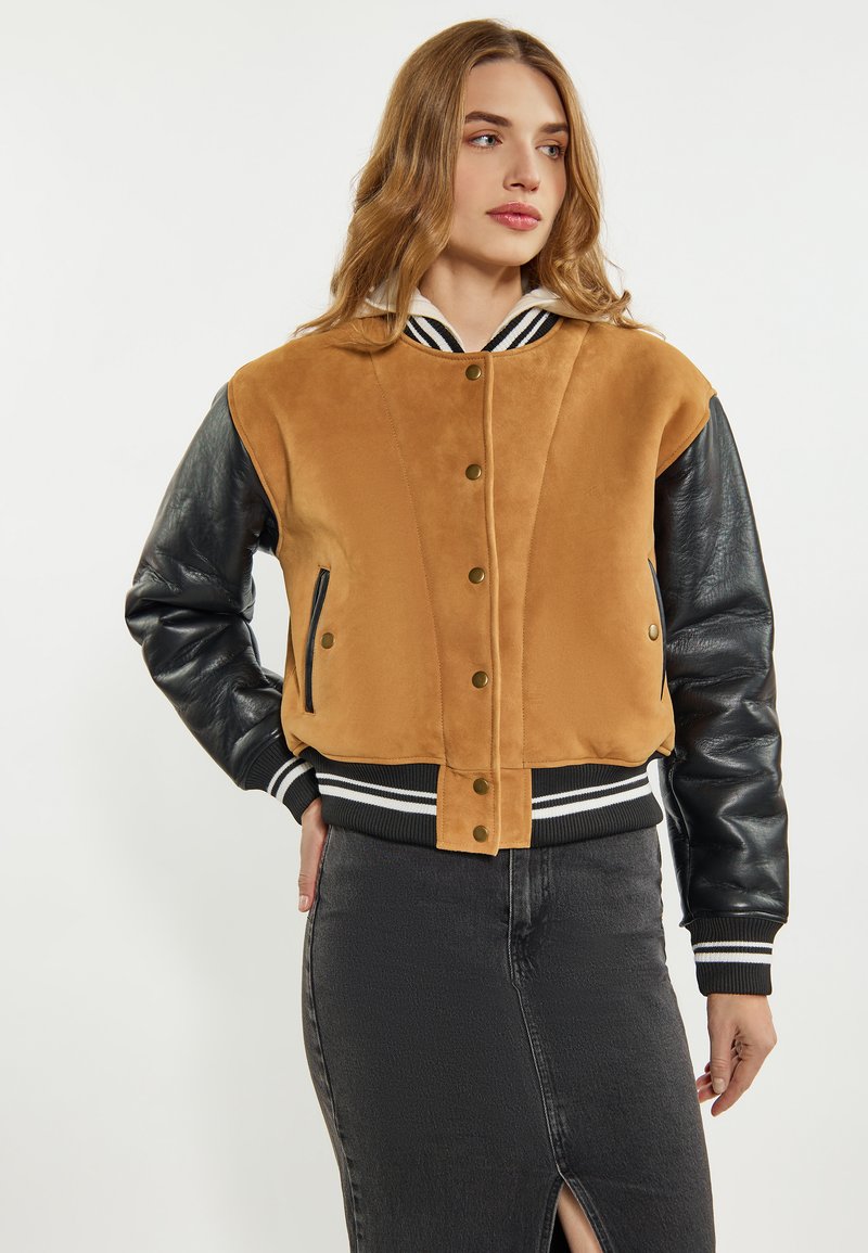 Giubbotto bomber in suede marrone con maniche in pelle nera, colletto e polsini a costine, dotato di chiusura con bottoni a pressione e due tasche laterali.