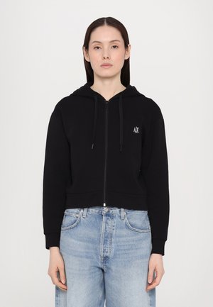Haut à capuche zippé noir coupé, fabriqué dans un matériau doux, avec une fermeture éclair à l'avant, une capuche à cordon réglable et un petit logo sur la poitrine.