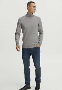 Halli turtleneck-svettar pehmeast kudumist, koos siniste teksadega. Riietus on ääretult sobiv ja ribakäistega, mida täiustavad mustad jalanõud.