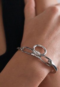 Silver bracelet featuring a smooth, glossy finish with linked chain and circular accents. Designed for a snug fit on the wrist.