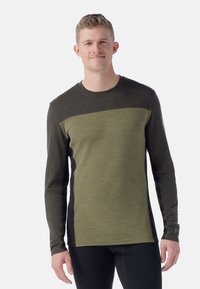 Dark green long-sleeve shirt featuring a textured, lighter green panel across the chest, with black side accents and a crew neckline.
