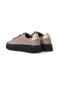 Lichtroze leren sneakers met zwarte veters en geribbelde zwarte zolen. Gouden accenten op de hak. Ronde neus en laag ontwerp.