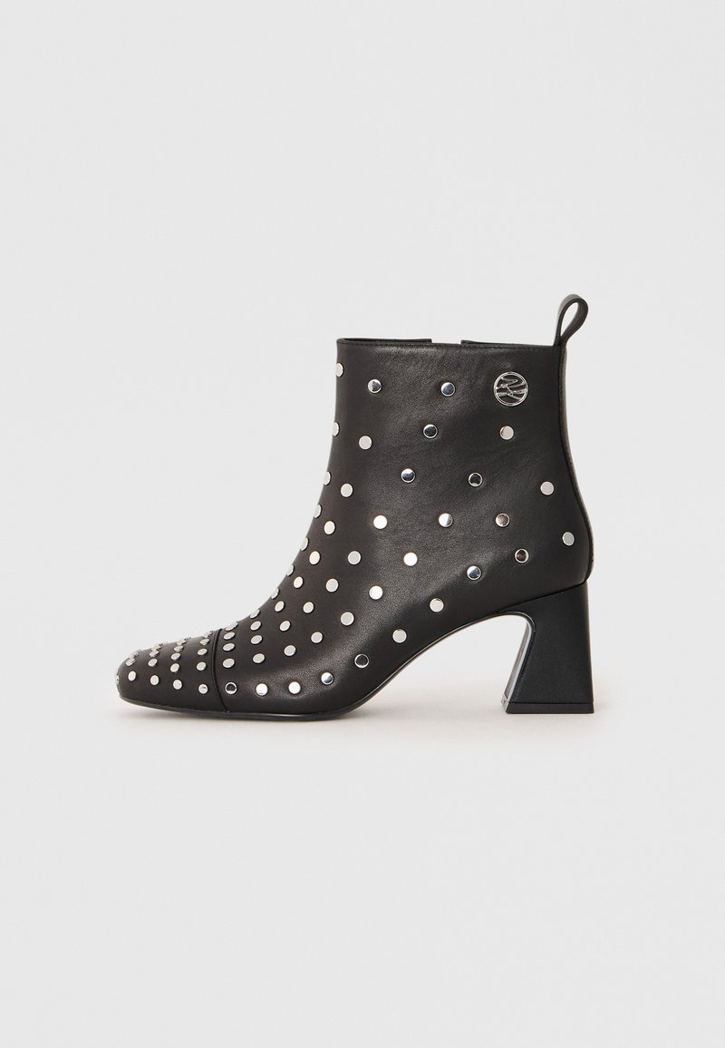 Black leather ankle boot with silver metal stud accents, pointed toe, and a chunky heel. Features a pull tab on the back for easy wear.