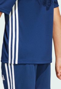 Námořnický modrý sportovní set skládající se z trička s krátkým rukávem a kalhot, vyrobený z hladké látky, s bílými třípruhovými akcenty po stranách.