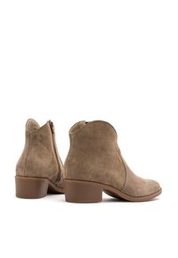 Para beżowych zamszowych botków za kostkę z niskimi, blokowymi obcasami i zamkami błyskawicznymi z boku, pokazanych z kąta tylnego i bocznego na białym tle.