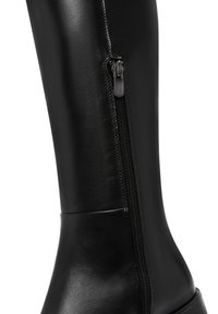 Botte noire en cuir à hauteur de genou avec une fermeture éclair sur le côté et une texture lisse. Dotée d'un bout arrondi et d'une semelle robuste, convient à diverses occasions.