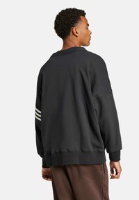 Sort pullover sweatshirt med afslappet pasform, ribbede manchetter og kant, med tre hvide striber på venstre ærme. Blødt bomuldsblandet materiale.