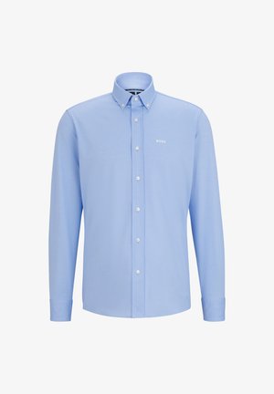 Camisa de manga longa azul clara com colarinho abotoado, fecho frontal com botões e pequeno logotipo branco no lado esquerdo do peito. Textura de tecido suave.