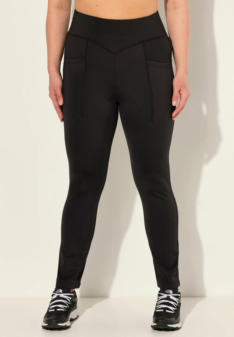 Zwarte sportlegging met een hoge taille, voorzien van twee zakken aan de voorkant, gebogen stikdetails en een strakke, gladde textuur.