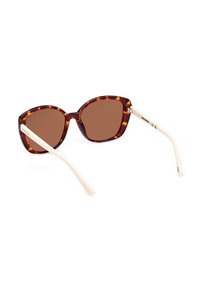 Bruin getinte zonnebril met een schildpadprint montuur en crèmekleurige pootjes. Cat-eye vorm met een gladde, glanzende afwerking.