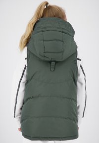 Gilet imbottito verde con un grande cappuccio, caratterizzato da un design trapuntato e una parte posteriore sartoriale. Maniche bianche con un accento laterale a fantasia.