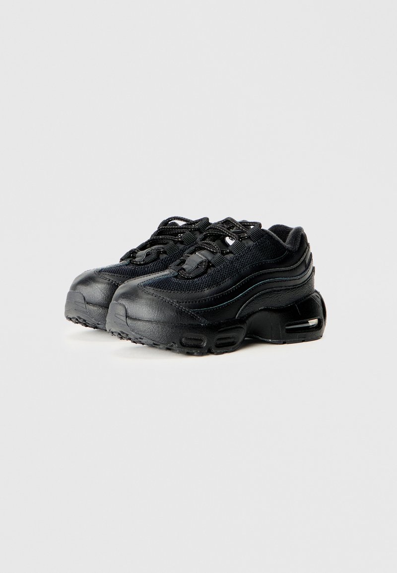 Une paire de baskets de sport noires avec des semelles texturées, des tiges en cuir et en mesh, et un amorti d'air visible dans les talons sur un fond uni.