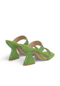 Groene suède hakken met een geometrische, versierde hak en brede banden. Het ontwerp heeft glinsterende groene studs voor extra detail.