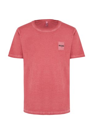 T-shirt rossa in cotone con maniche corte, colletto rotondo e un piccolo logo bianco "Moschino" su una tasca. Tessuto morbido con un leggero effetto di sbiadimento.