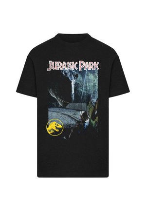 Mustat t-paidat, joissa on "Jurassic Park" -teksti, dinosauruksen pää kohoaa istuvan miehen ylle lähellä ajoneuvoa, ja alla on keltainen dinosauruksen logo.