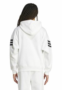 Felpa bianca con cappuccio e vestibilità comoda. Caratterizzata da un design a tre strisce nere sulle maniche e polsini a coste. Materiale morbido con una texture liscia.