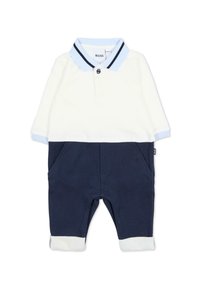 Ensemble deux pièces bleu marine comprenant un haut polo blanc avec des accents bleu clair, une fermeture à boutons, et un pantalon bleu marine avec des poches avant et des ourlets à revers.
