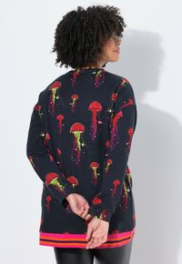 Camiseta de manga larga en color marino con un estampado de medusas en rojo, verde y rosa; dobladillo de rayas brillantes; tejido suave y texturizado; corte relajado.