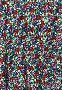 Motif dense de petites fleurs multicolores avec des fleurs rouges, vertes, bleues, violettes et blanches sur un fond de tissu texturé.