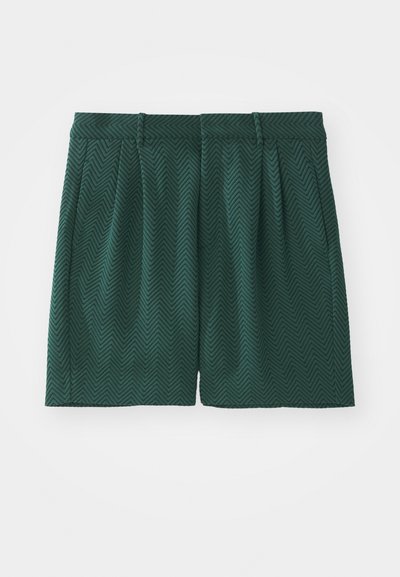 Dunkelgrüne Shorts aus strukturiertem Stoff mit Fischgrätenmuster. Mit Falten und einem Bund ausgestattet, in knie-langer Schnittform.