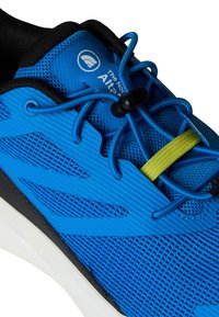 Modra športna čevlja z teksturirano mrežasto zgornjo plastjo, črnimi poudarki in rumenim zategovalcem za vezalke, z belo srednjo podplatom in logotipom.