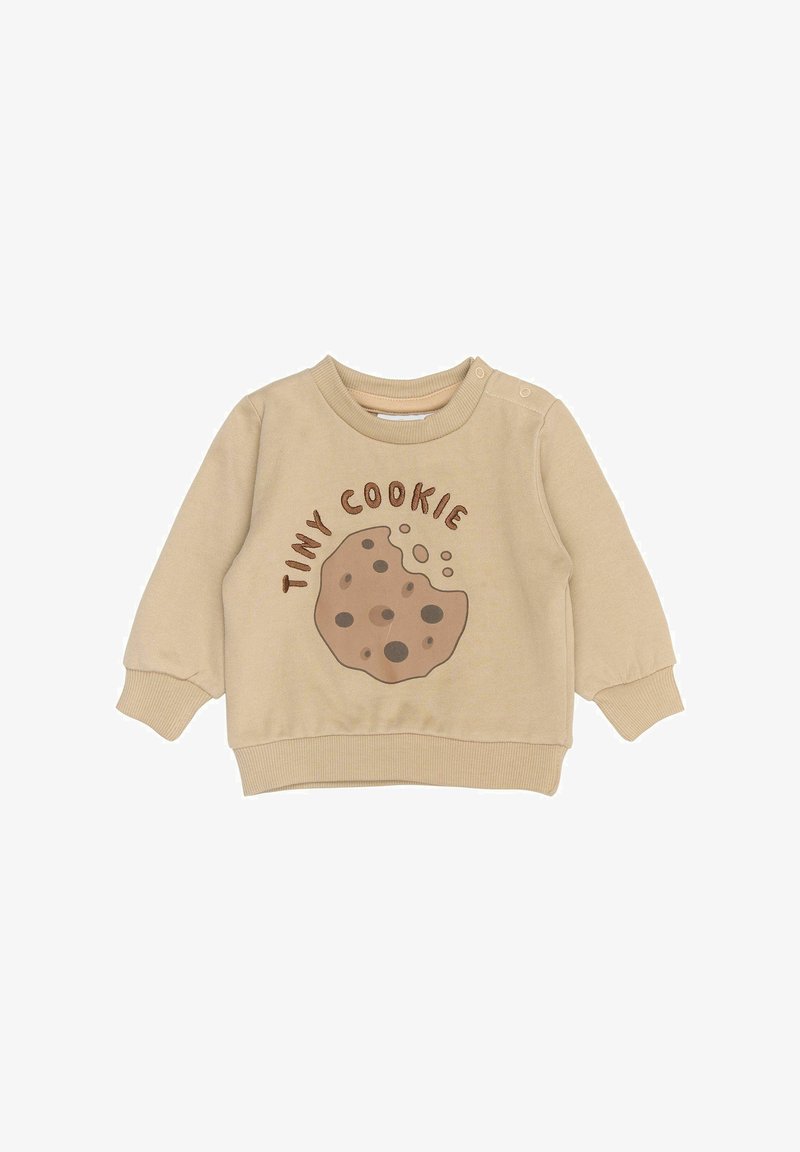 Beige pulóver cookie grafikával, amelyen sötét csokoládé chips akcentusok találhatók, és a "TINY COOKIE" felirat. Kerek nyakkivágással és bordázott mandzsettával rendelkezik.